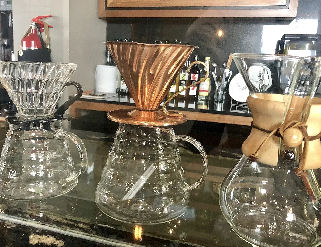 Mehrere Handfilter und Glaskannen nebeneinander auf einer Theke.