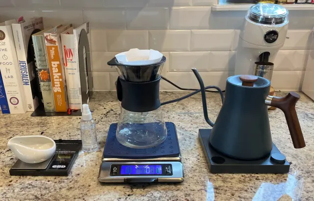 Kaffeeplatz mit Handfilter, Glasserver, Digitalwaage und Schwanenhalskessel.