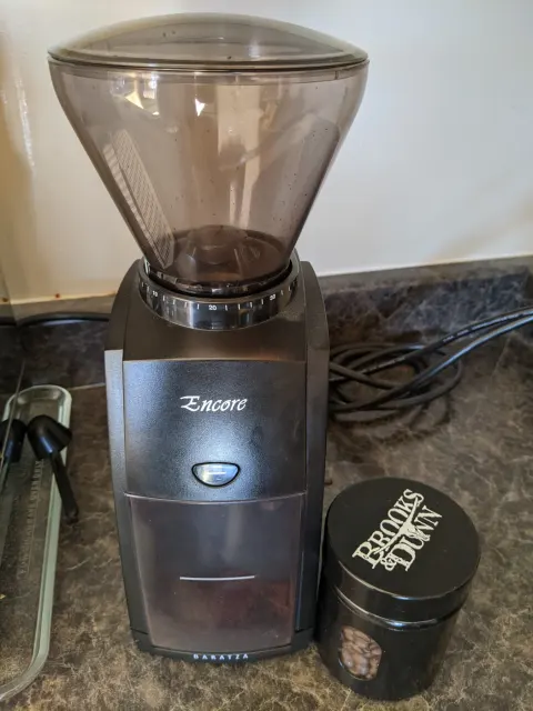 Elektrische Baratza-Encore-Kaffeemühle mit Bohnenbehälter und separater Kaffeepackung.