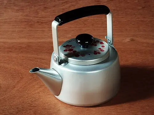 Teekanne aus Aluminium mit Bügelgriff, kurzer Tülle und bemaltem Deckel.