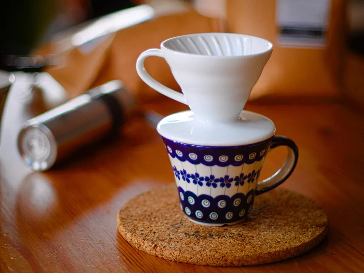 Weißer Hario-V60-Handfilter auf einer gemusterten Tasse.
