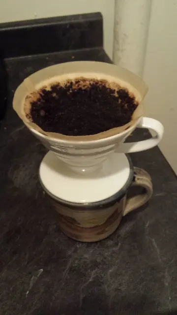 Hario-V60-Handfilter mit Papier und nassem Kaffeemehl während des Aufgusses.