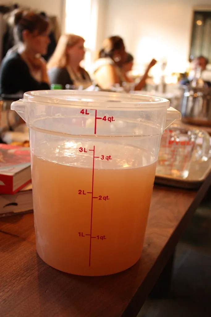 Messbecher mit orangefarbener Flüssigkeit und sichtbarer Skala auf einem Tisch