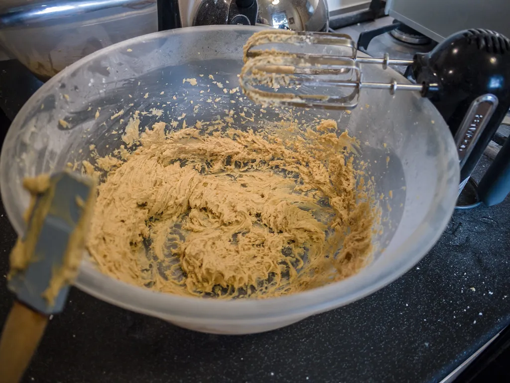 Gläserne Rührschüssel mit Erdnussbuttercreme und den Rührbesen eines Handmixers