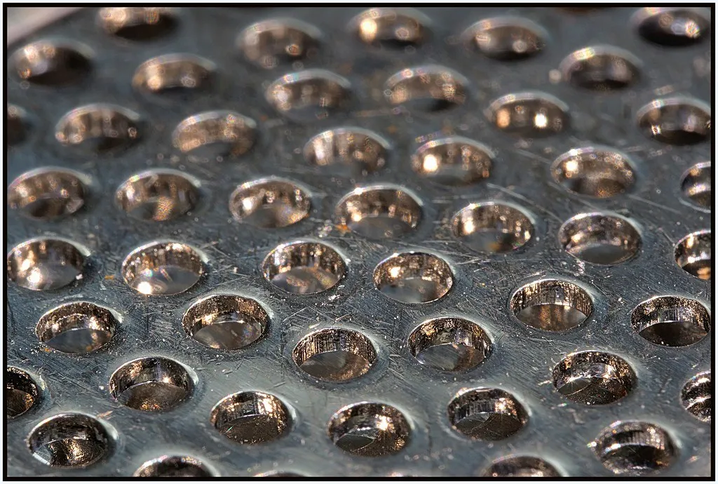 Nahaufnahme der runden Austrittsöffnungen einer Knoblauchpresse aus Metall