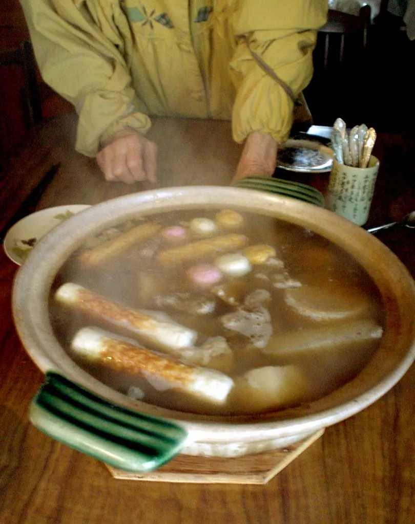 Großes rundes Kochgefäß mit Oden und einer Schöpfkelle auf einem Holztisch