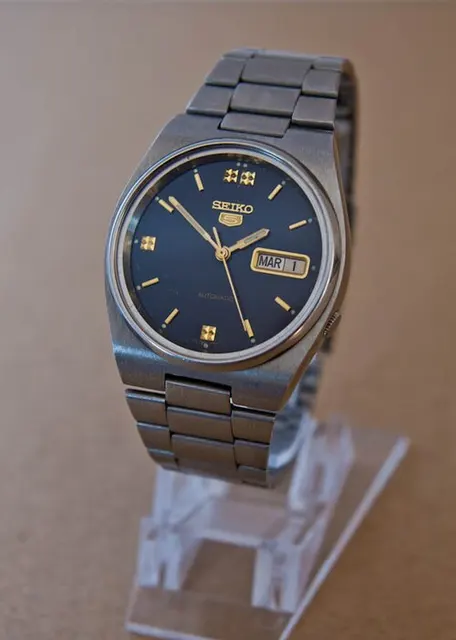 Seiko 5 automático de esfera azul con detalles dorados y brazalete metálico.