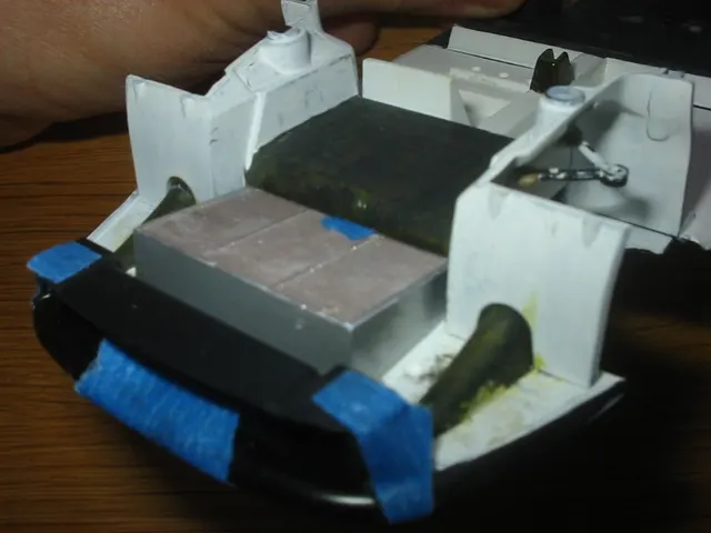Otra vista de piezas de una maqueta Tamiya Porsche 911 GT1 con cinta azul junto a sus bordes.