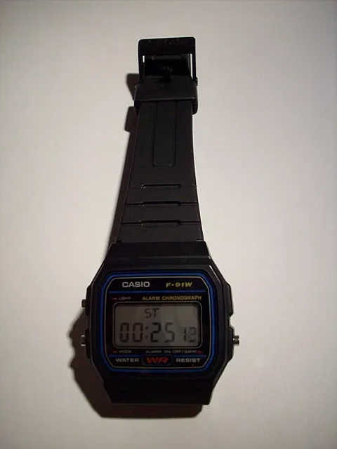 Casio F-91W con el cronómetro en pantalla y la correa extendida.
