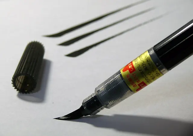 Punta de un rotulador pincel japonés junto a trazos de tinta.