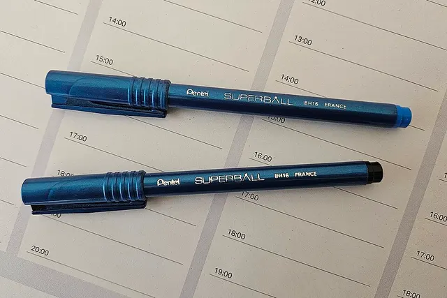 Dos bolígrafos Pentel Superball BH16 azules sobre una agenda.