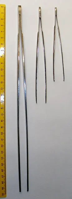 Pinzas de laboratorio de distintas longitudes junto a una regla.