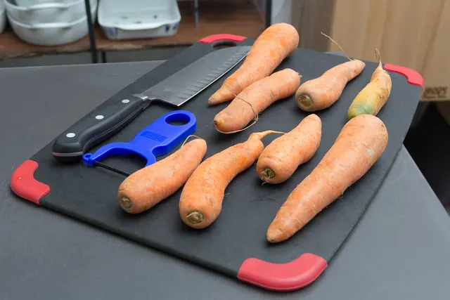 Zanahorias, pelador y cuchillos sobre una tabla.