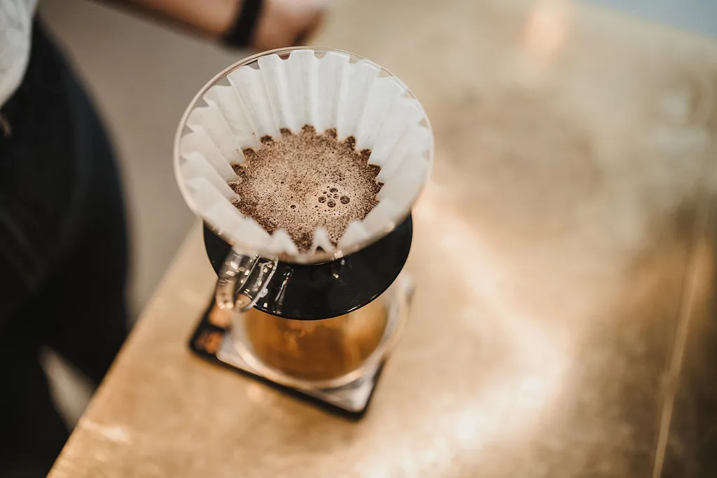 Café molido y filtro de papel en un dripper.