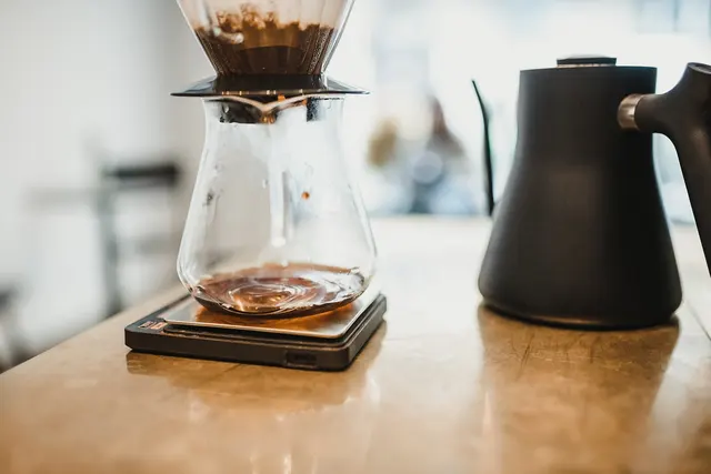 Jarra de café, dripper y hervidor sobre una encimera.