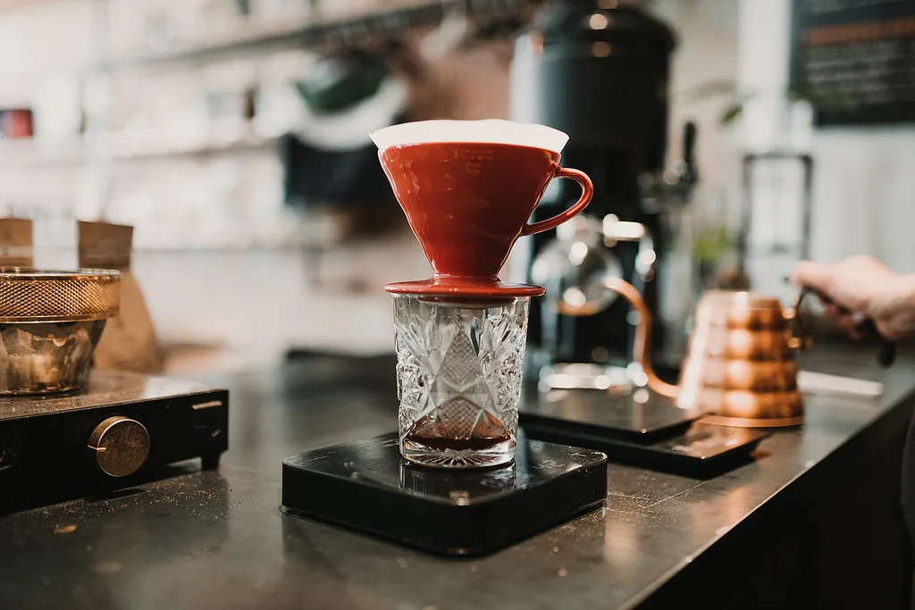 Dripper rojo sobre una taza y una báscula de café.