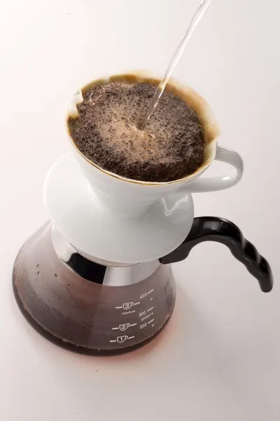 Dripper blanco con filtro sobre una jarra de café.