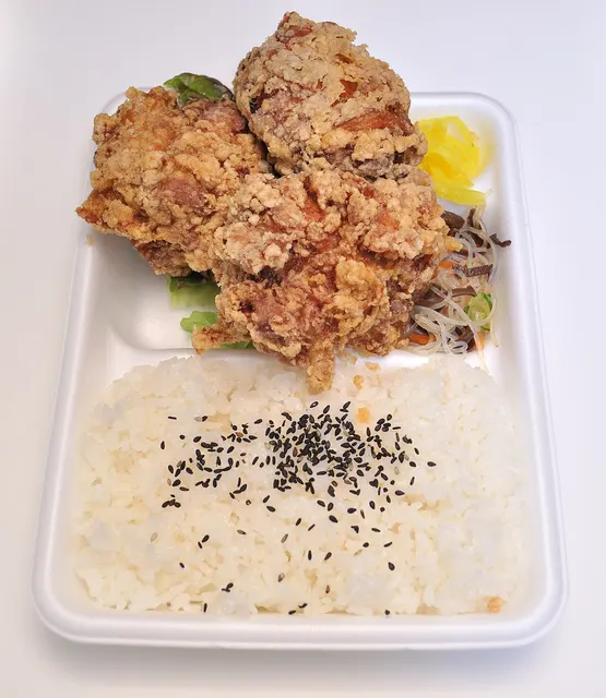 Bento con arroz y piezas empanadas en una bandeja blanca.