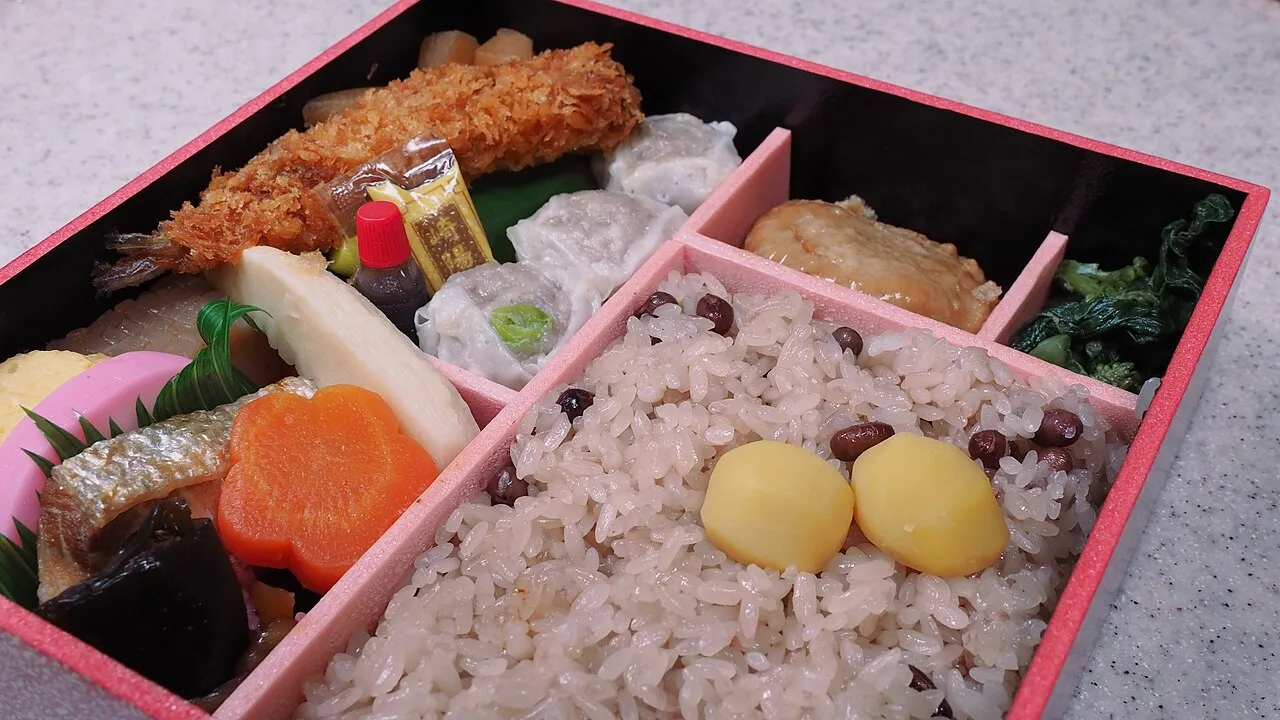 Bento de varios compartimentos con arroz y acompañamientos.