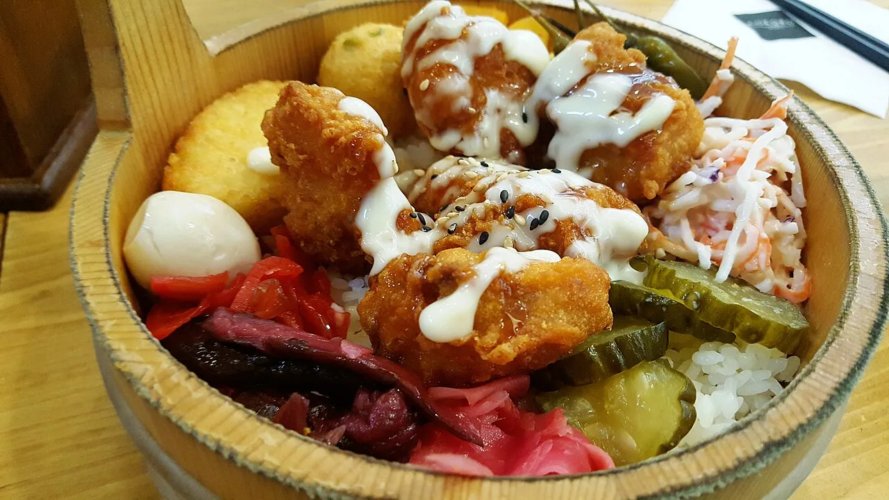 Comida servida en un recipiente redondo con diferentes acompañamientos.