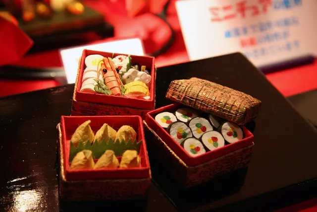 Varias cajas de comida japonesas abiertas sobre una mesa.