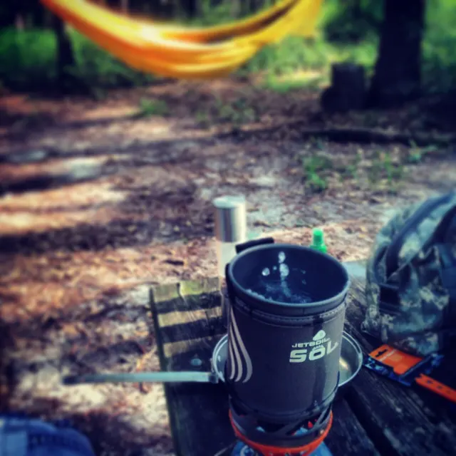 Sistema de cocina Jetboil SOL sobre un cartucho de gas en un campamento. Fotografía ilustrativa de cocina al aire libre; no es un SOTO WindMaster.