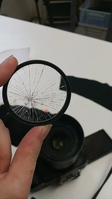 Filtre photographique cassé tenu devant un appareil.