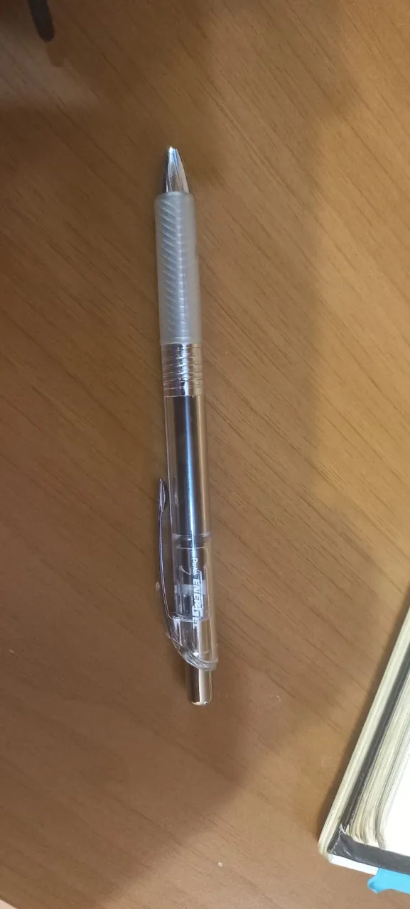 Stylo Pentel EnerGel à encre noire posé sur un bureau en bois