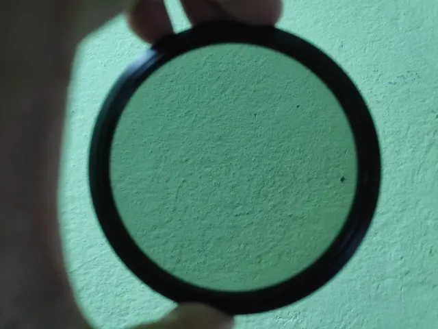 Filtre ND circulaire tenu devant un mur clair