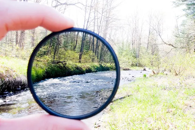 Filtre ND tenu devant une rivière pour montrer l’atténuation de la lumière