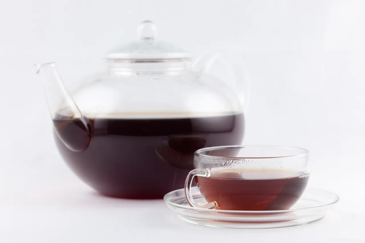 Théière et tasse en verre remplies de thé sur un fond clair