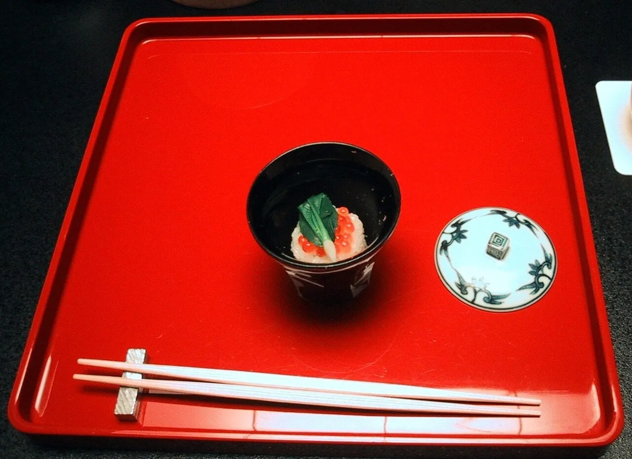 Petit service japonais sur plateau rouge avec bol, petite assiette et baguettes