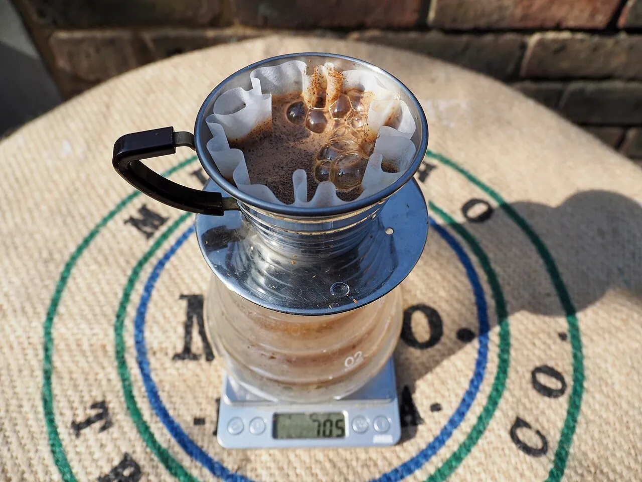 Kalita Wave avec filtre plissé posé sur une carafe et une balance