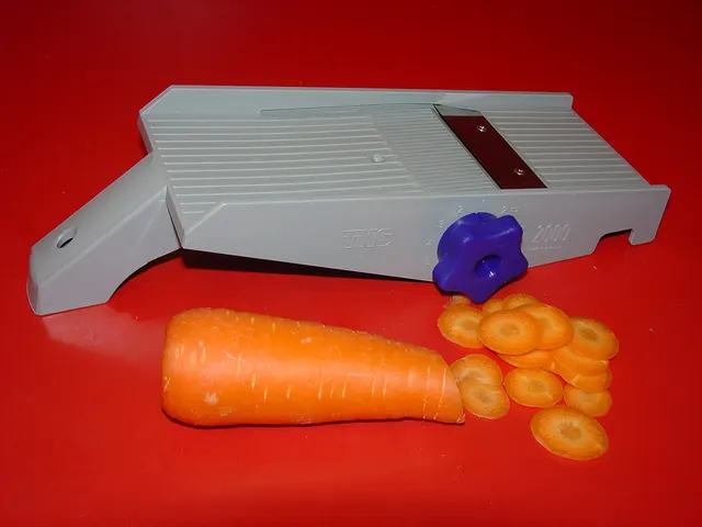 Mandoline et carotte découpée en rondelles sur un fond rouge