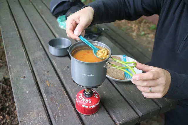 Préparation d’un repas sur un petit réchaud à gaz en extérieur