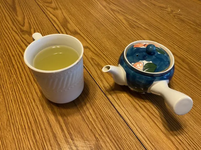 Grüner Gyokuro-Tee in einer Tasse neben einer blau bemalten Kyūsu.