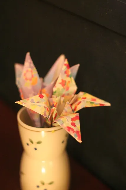 Bunte gefaltete Papierblüten in einer cremefarbenen Vase