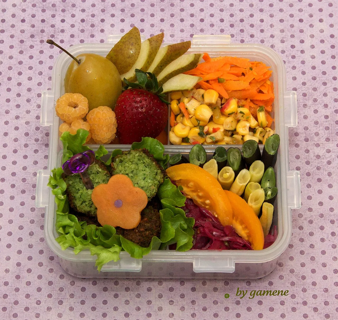 Bento a scomparti con falafel, insalate di carote e mais, verdure e frutta.