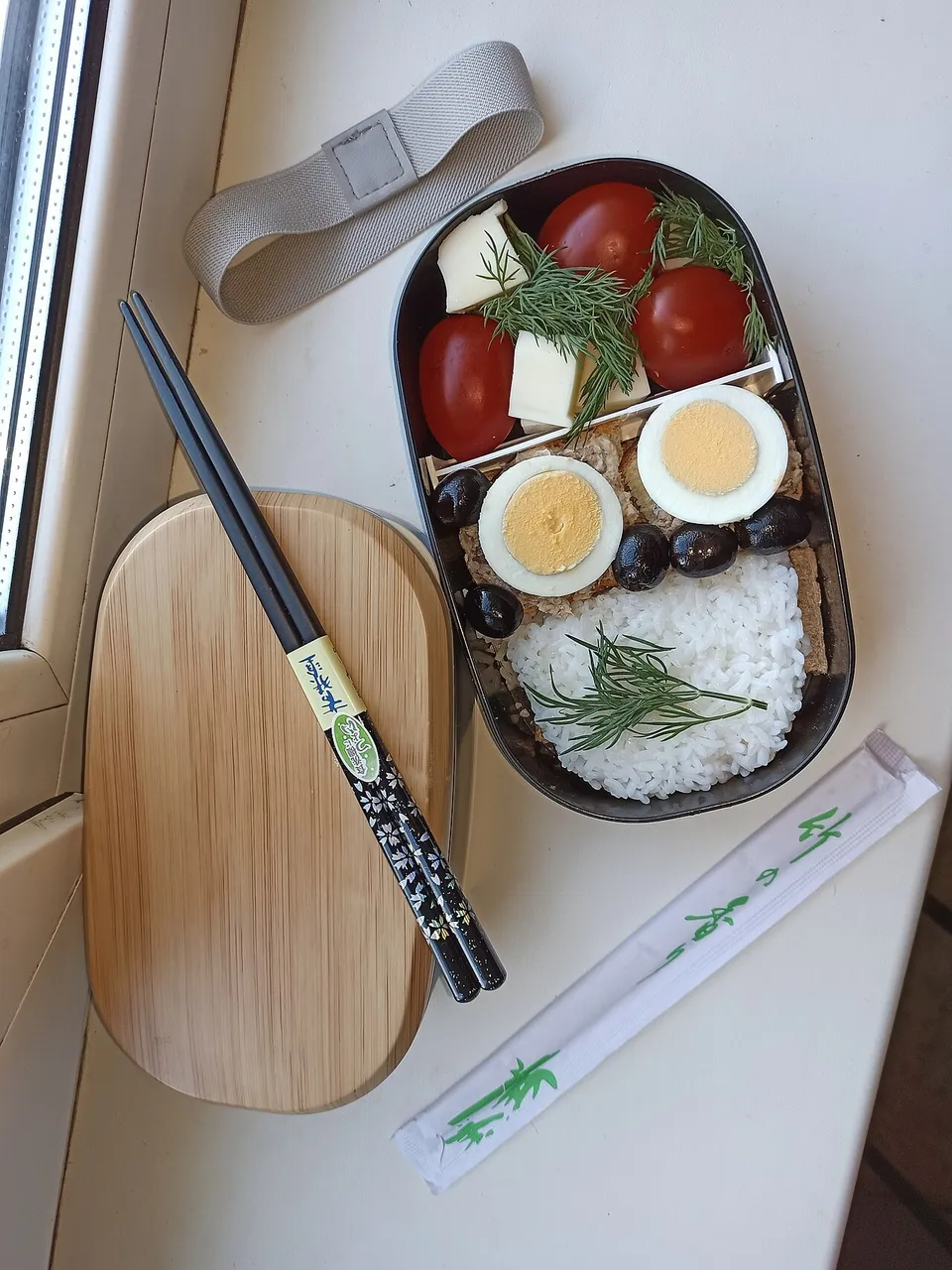 Bento aperto con riso, uovo e verdure accanto al coperchio