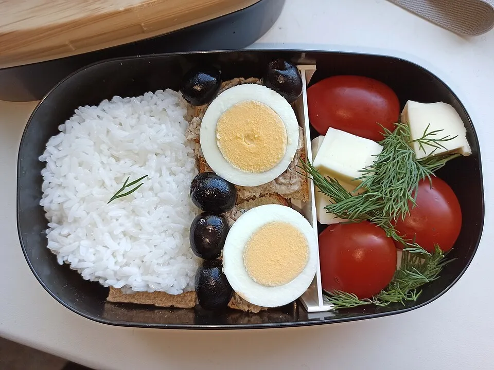 Bento con riso, uovo sodo e verdure disposto in un contenitore aperto