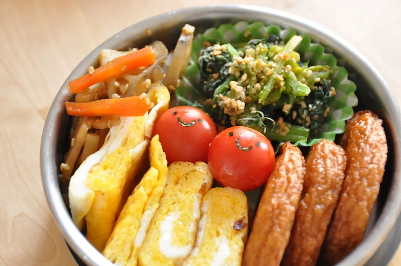 Un bento rotondo aperto con verdure e frittata disposte nello stesso vano