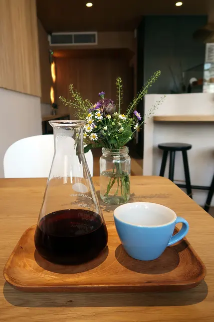 Caraffa di vetro con caffè filtro accanto a una tazza azzurra