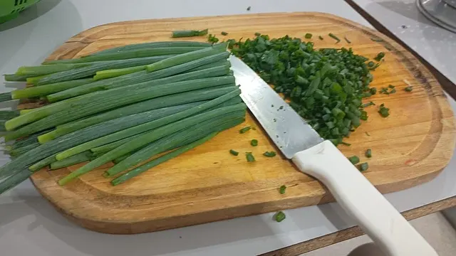 Taglio di cipollotto su un tagliere di legno