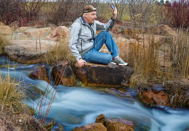 Fotografo accanto a un corso d’acqua con effetto di lunga esposizione