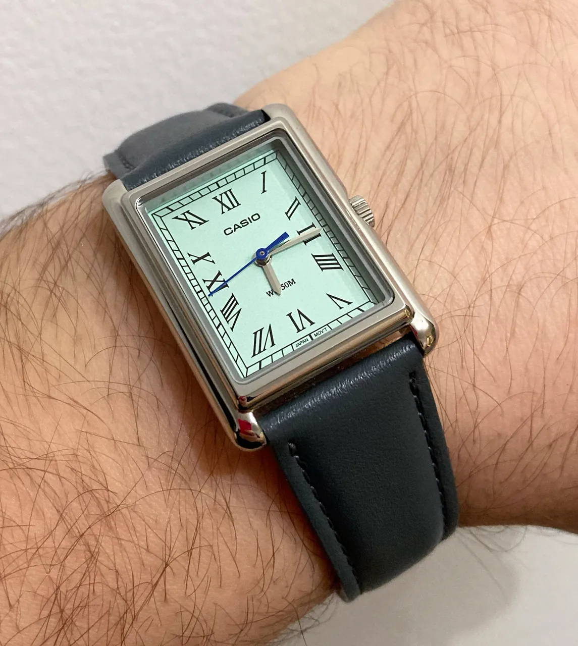 Casio rettangolare con quadrante chiaro e cinturino grigio al polso