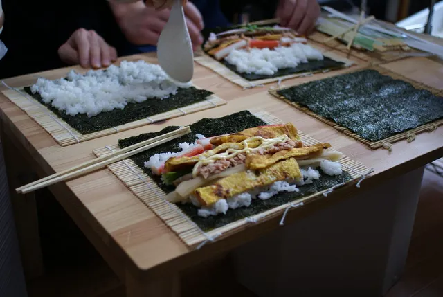 Reis und Zutaten auf Nori-Blättern und Bambusmatten bei der Zubereitung von Eho-maki