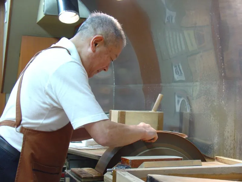 Handwerker in Kyoto beim Schärfen einer japanischen Küchenmesserklinge.