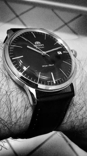 Orient Bambino med mörk urtavla och svart läderband på handleden.