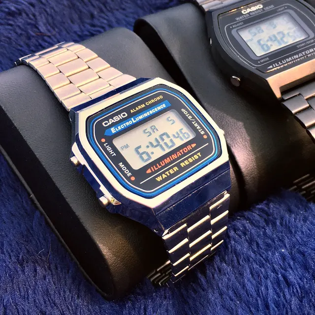 Digital Casio med blå ram runt displayen och metallarmband.