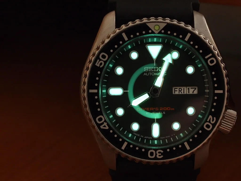 Seiko SKX007J i mörker med grönt lysande visare och timmarkeringar.